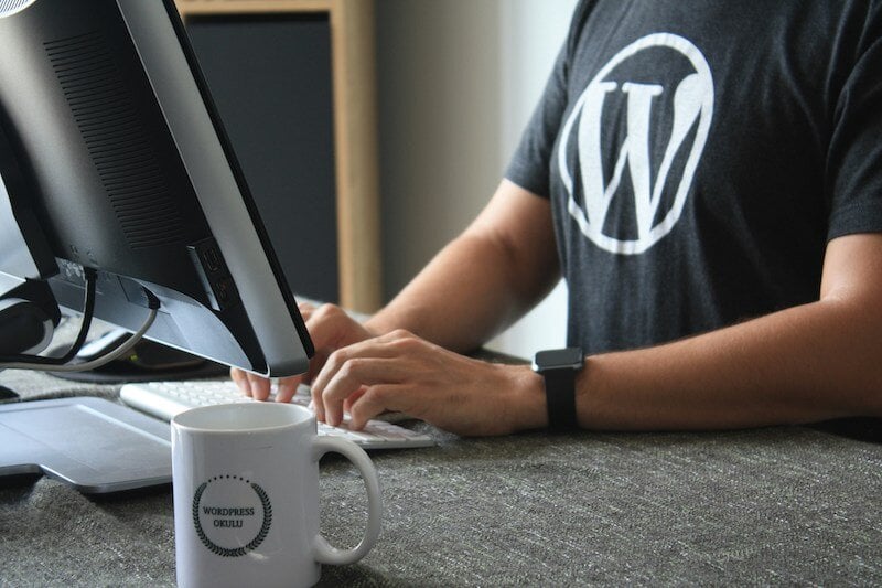 Male using desktop computer and wearing a WordPress tshirt